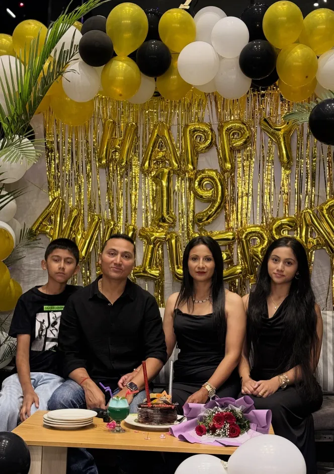 A family celebrating an anniversary with gold and black balloons on the rooftop