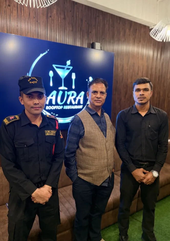 Aura staff standing in front of the illuminated Aura Rooftop logo wall